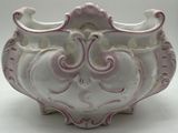 a white and pink vase sitting on a white surface