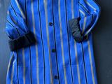 un manteau rayé bleu et jaune accroché à un mur noir