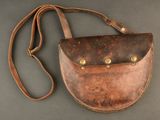 a brown leather purse with a strap on a gray surface