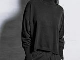 a black and white photo of a woman in a turtle neck sweater and wide legged pants