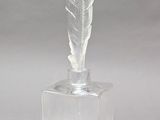 clear acrylic sculpture of a feather with a yellow feather tip