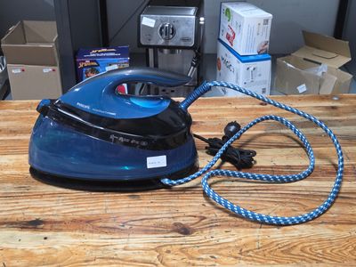 a blue and black steam iron sitting on a wooden table
