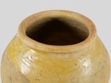 a yellow vase sitting on a table with a white background