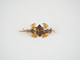 a close up of a gold broochle with leaves on it