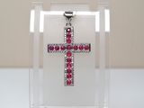 un gros plan d'une croix composée de pierres rouges dans une boîte transparente