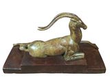 statue of a goat on a wooden base with a long horn