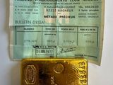 un lingot d'or posé à côté d'une feuille de papier