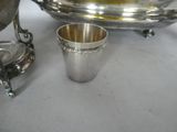 a silver cup sitting on a table next to a silver plate