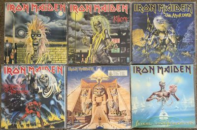 several iron maiden cds are stacked on a wooden table