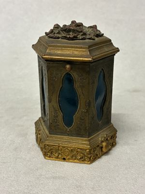 une petite horloge dorée et bleue posée sur une surface blanche