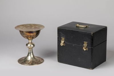 une boîte noire et une tasse argentée posées l'une à côté de l'autre