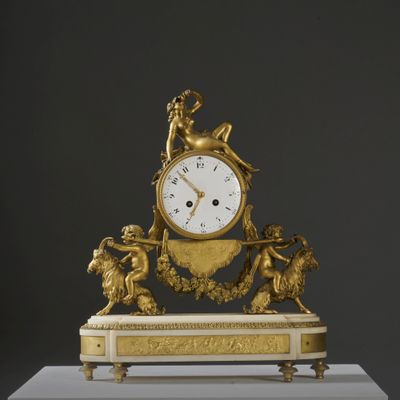 a gold clock sitting on top of a white pedestal