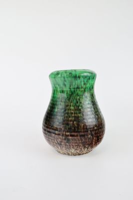 a green and brown vase sitting on a white surface