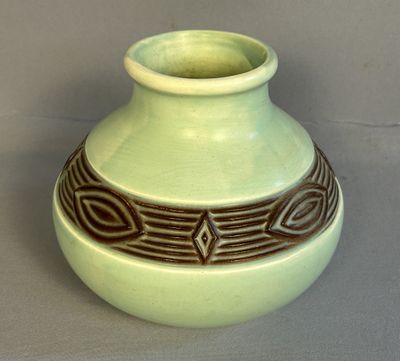 un vase vert orné d'un motif marron