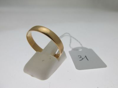 une bague en or et une étiquette blanche posée sur une table blanche