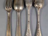 three silver spoons and a fork are lined up on a table