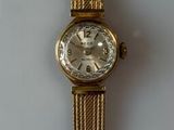 une montre en or sur une surface blanche avec un fond blanc