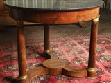une table ronde avec un plateau en marbre posée sur un tapis rouge