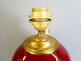 a red vase with a gold top on a table