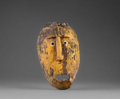 un masque en bois représentant un visage jaune sur fond gris