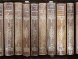 de nombreux livres anciens dans une boîte en bois posée sur une étagère