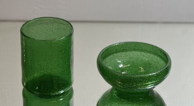 two green glass vases sitting on a white table