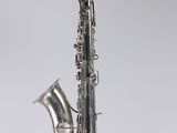 a silver saxophone sitting on top of a wooden stand