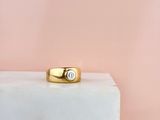 une bague en or sertie d'un diamant repose sur un bloc de marbre
