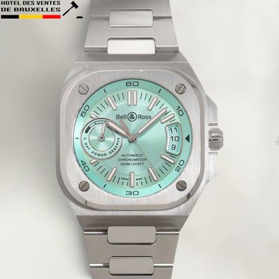 a silver watch with a green dial on it