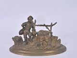 bronze figurine of a man sitting on a rock with a dog
