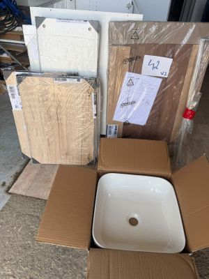 un lavabo blanc posé dans un carton posé par terre