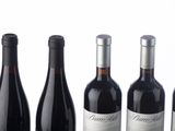 six bottles of wine are lined up in a row on a white surface