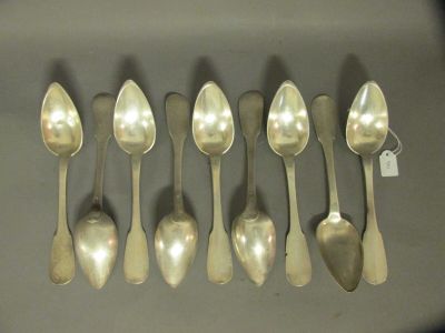 six cuillères en argent sont alignées sur une table
