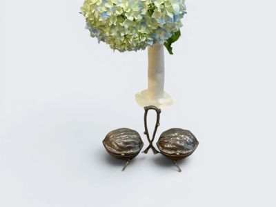 a white vase with blue and green flowers in it