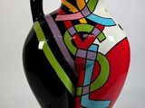 un vase coloré posé sur un socle noir, sur fond blanc
