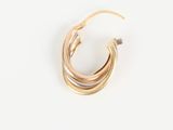 gros plan d'une paire de boucles d'oreilles en or sur une surface blanche