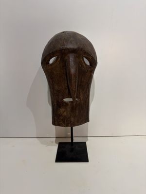 an image of a wooden mask on a stand on a white surface