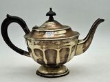an antique silver teapot with a black handle on a white surface