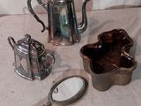 une théière en argent, une théière en argent et un miroir posé sur une table
