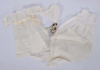 deux robes blanches et un ours en peluche posés sur une surface blanche