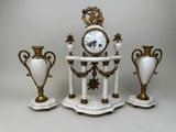 three white and gold vases and a clock on a table