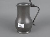 an antique pewware pitcher with a bird on the handle