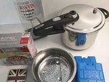 a silver pot with a lid sitting on a counter next to other items