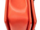 a close up of a red purse on a white surface