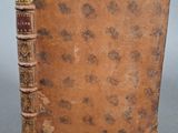 un vieux livre posé sur une table à côté d'un mur gris