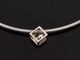 a close up of a silver necklace on a black surface