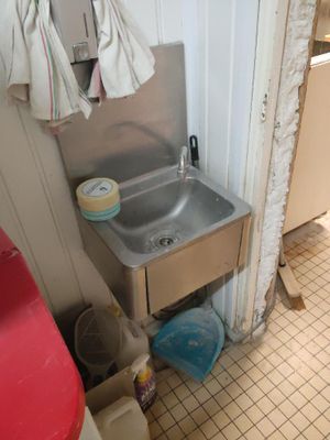 un lavabo dans un coin de la salle de bains, avec des toilettes rouges