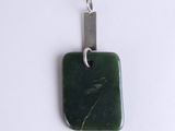 a green stone pendant with a silver clasp on a white surface