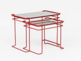 a pair of red metal tables with glass tops on a white background