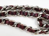 a close up of a silver chain with red beads on a white surface